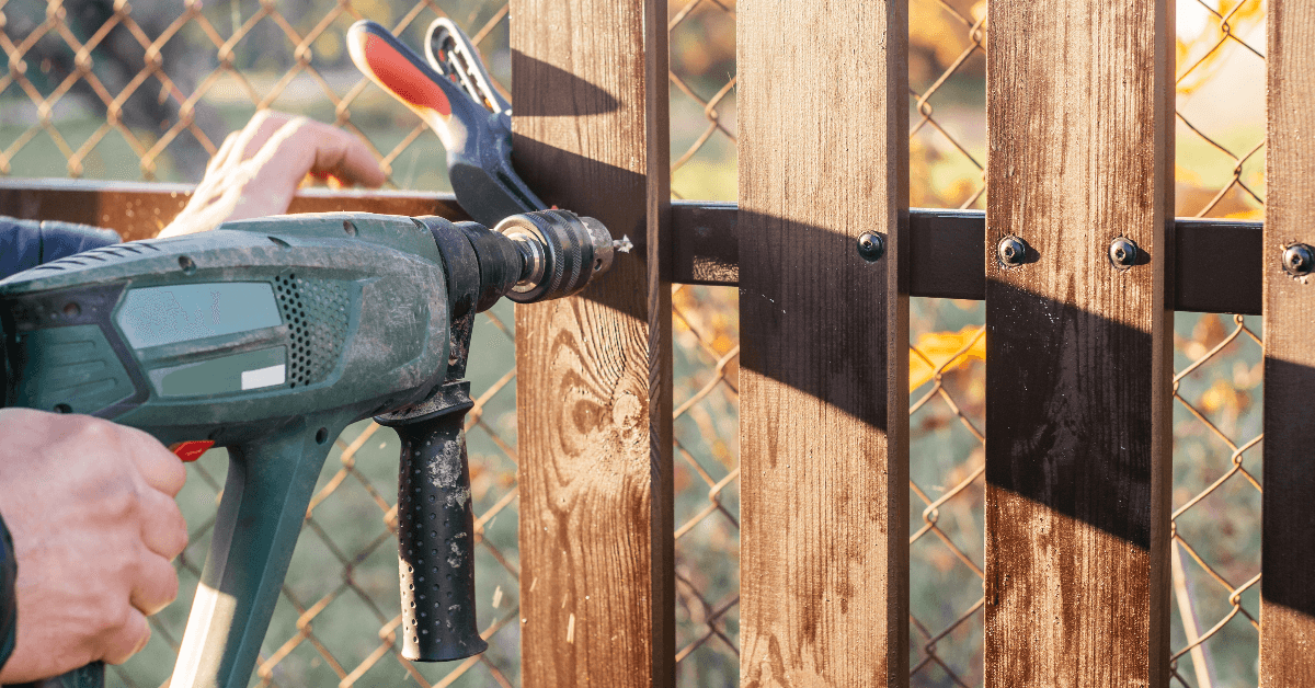 repairing fence hand of carpenter holding electric drill